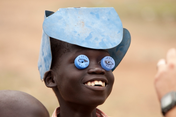 Making a mask out of bottle tops and an engine fan in South Sudan