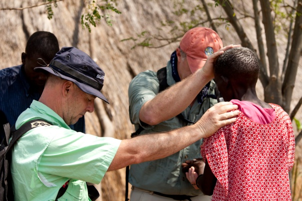 Missionaries pray for a sick woman in South Sudan.